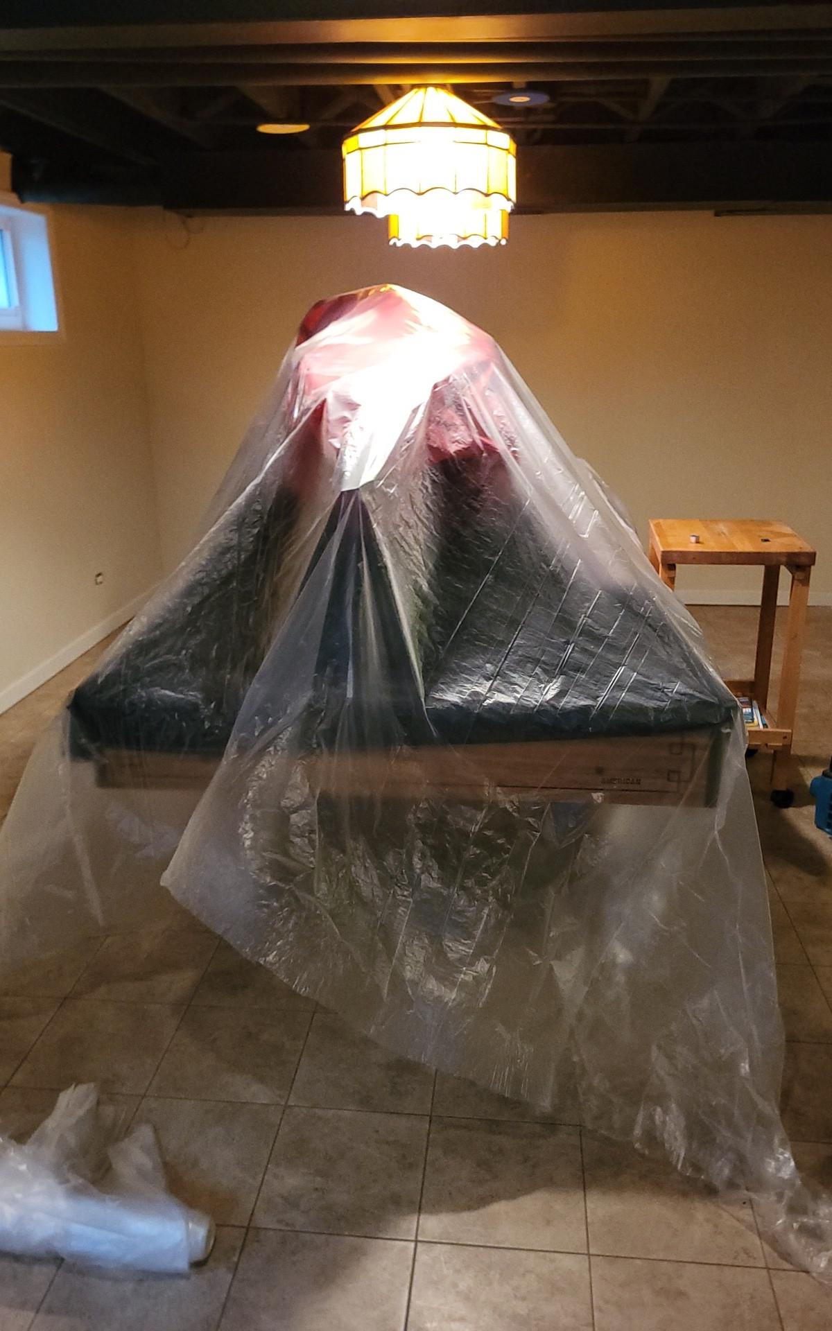 Pool table covered in protective plastic sheeting during basement drying in a Glen Ellyn home
