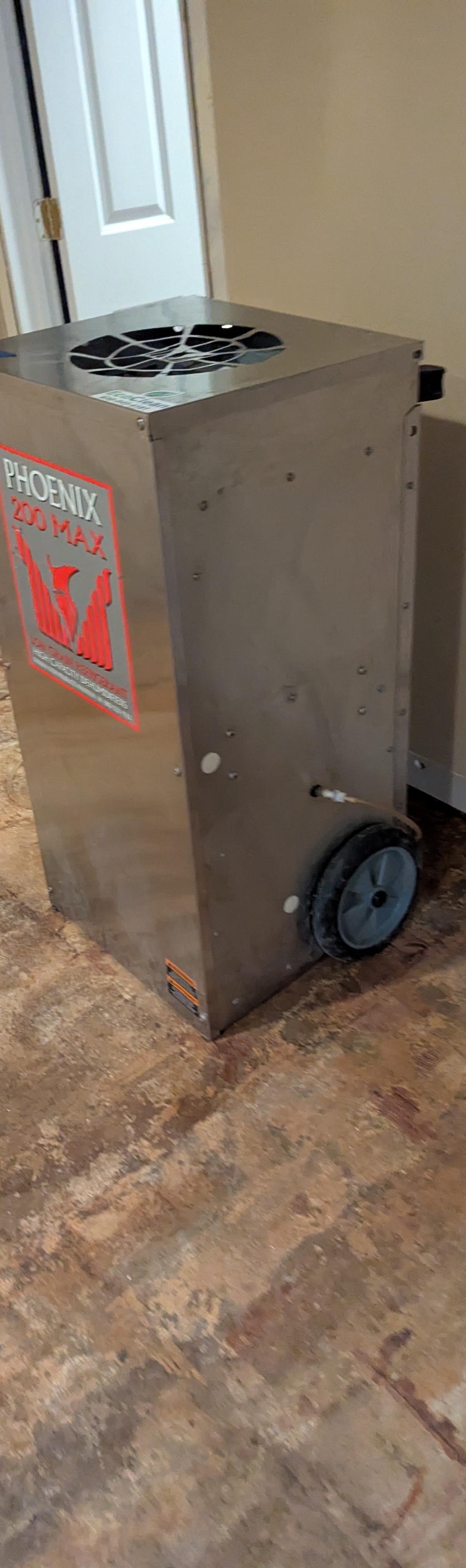 Dehumidifier drying a stripped subfloor after water-damaged flooring removal in a Glen Ellyn basement