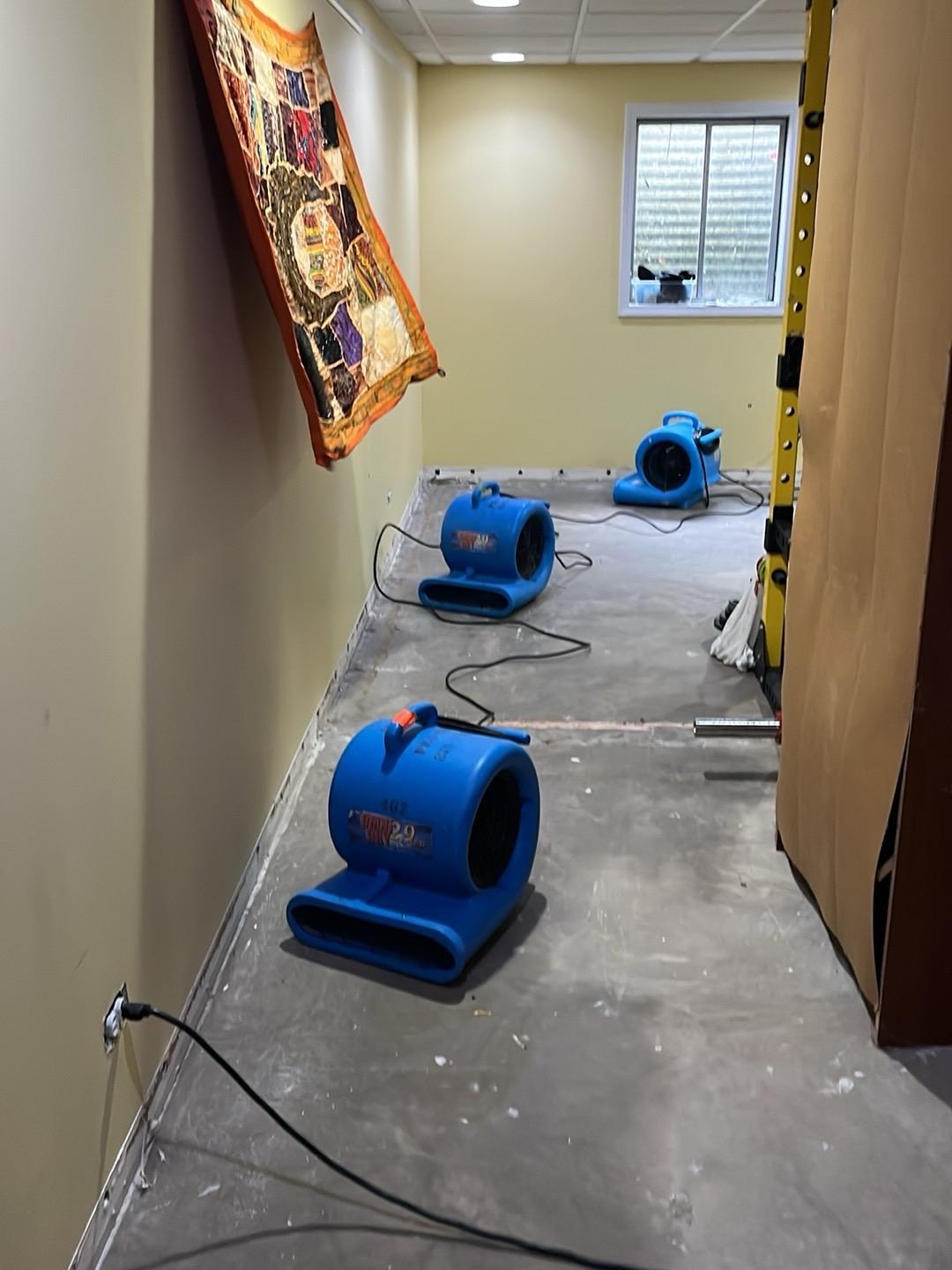 Three air movers drying a stripped hallway floor in a Naperville basement