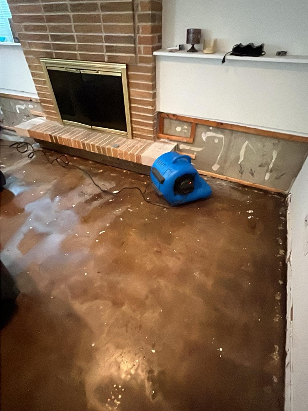 Air mover drying a Naperville family room after carpet removal, fireplace in view